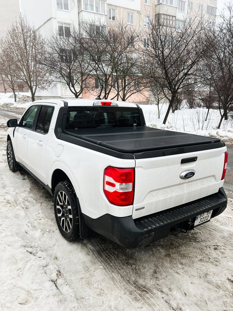White pickup parked on a snowy road with urban buildings in background
