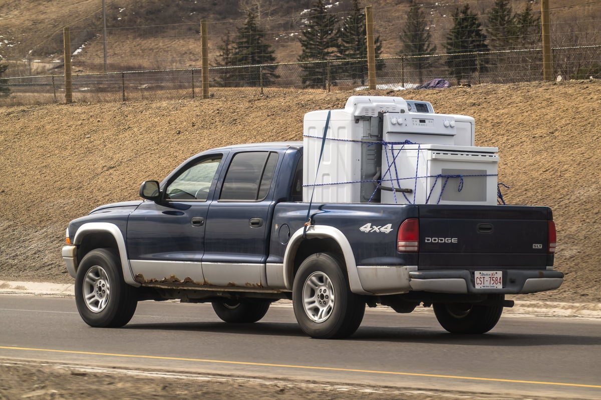 A blue Dodge Dakota pickup truck hauls a heavy load on a highway in Calgary, Alberta, Canada
