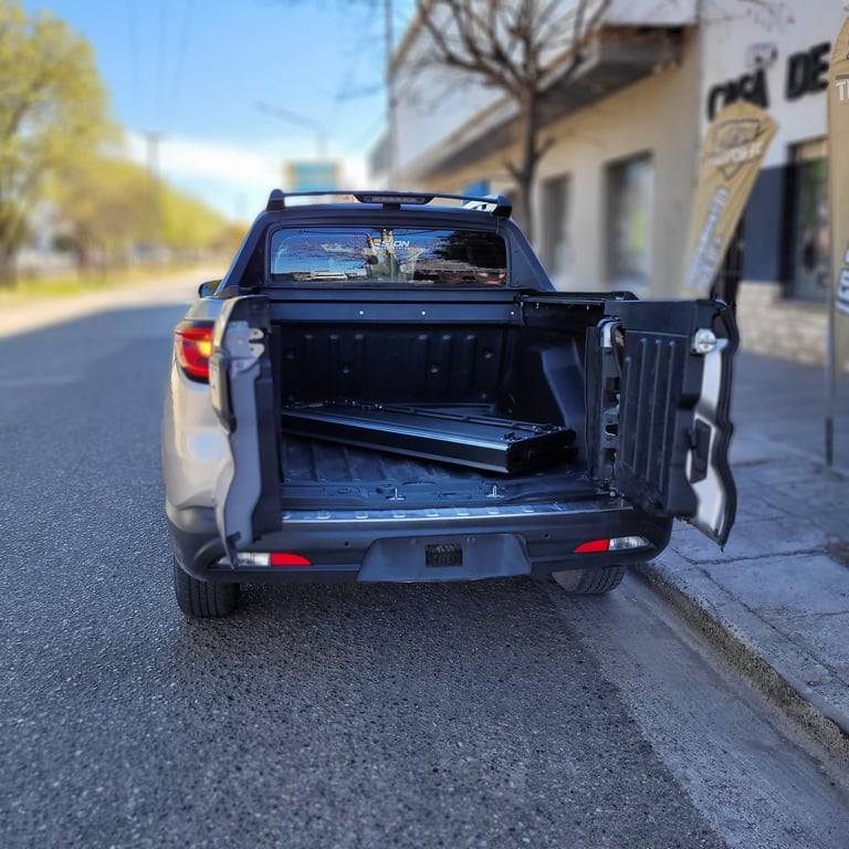 Black pickup truck with open tailgate and extended bed parked on a residential street