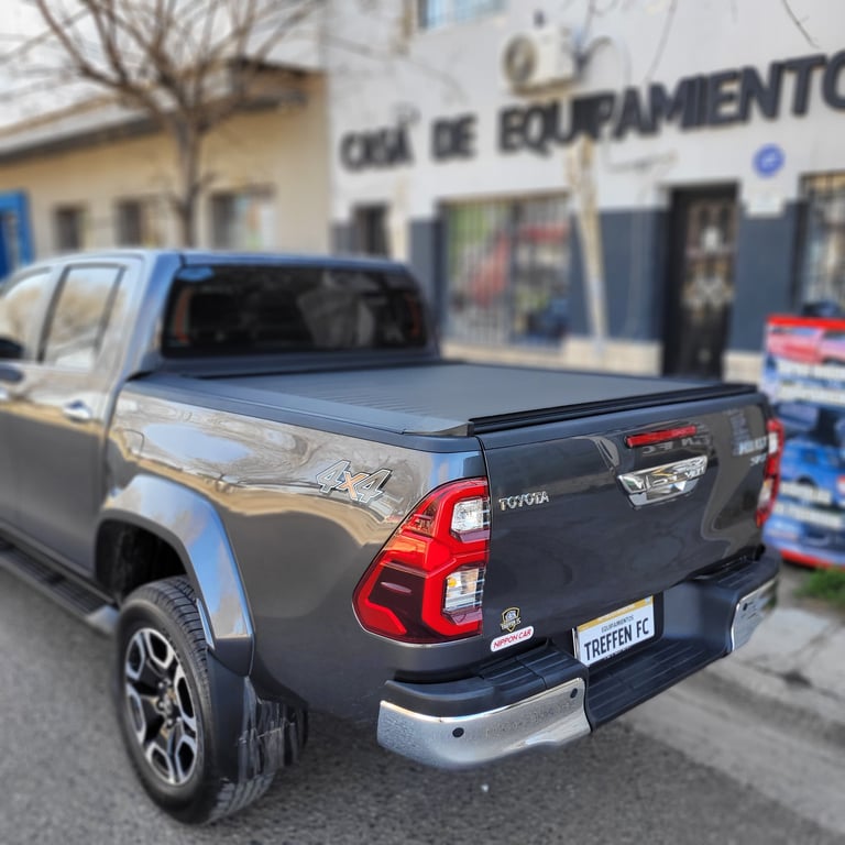 Blue Toyota pickup truck with tonneau cover in parking lot outside commercial building