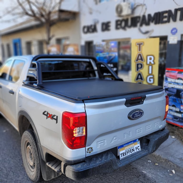 White Ford Ranger pickup truck with black tonneau cover and French license plate parked outside a hardware store