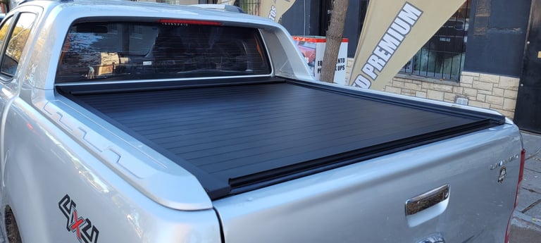 Silver pickup truck with black tonneau cover over the truck bed, parked on street