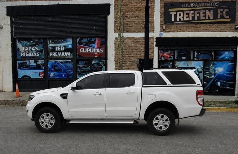 White pickup truck parked on street in front of storefronts including Treffen FC shop