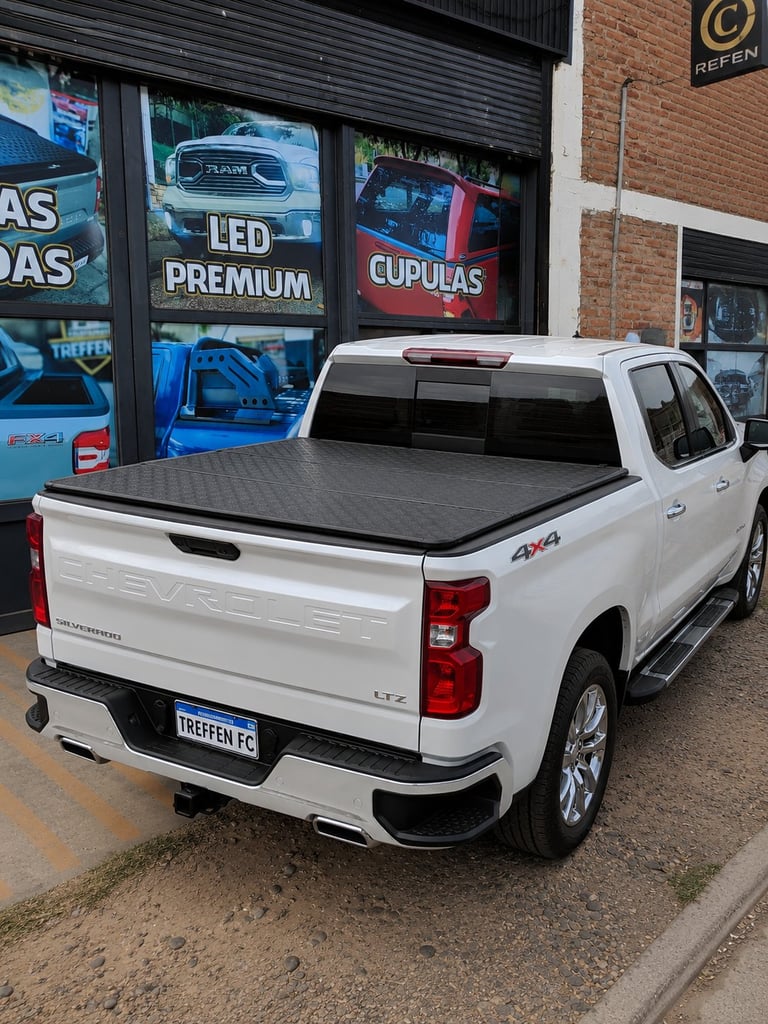White pickup truck with tonneau cover displayed outside auto shop storefront with LED lighting signs