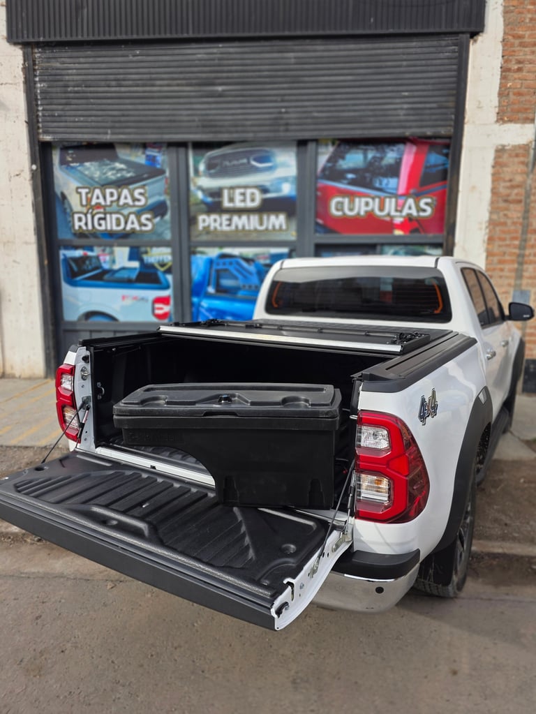 White pickup truck with open tonneau cover displayed outside automotive shop showing truck bed storage solution
