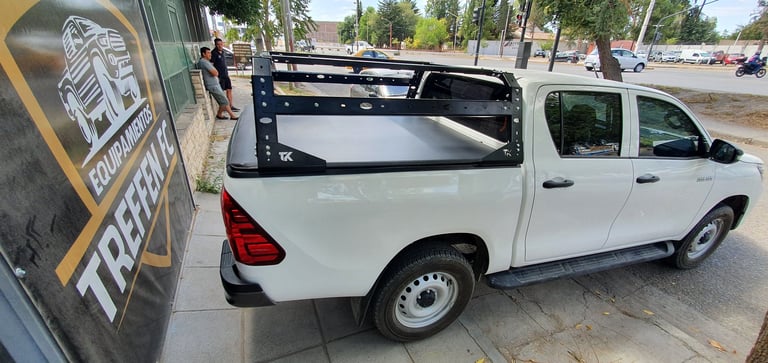White pickup truck with open bed parked on street next to storefront with yellow signage