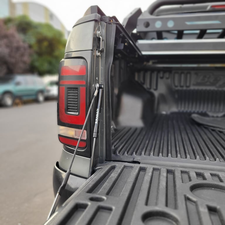 Close-up of a pickup trucks open bed with red taillight and textured bed liner visible
