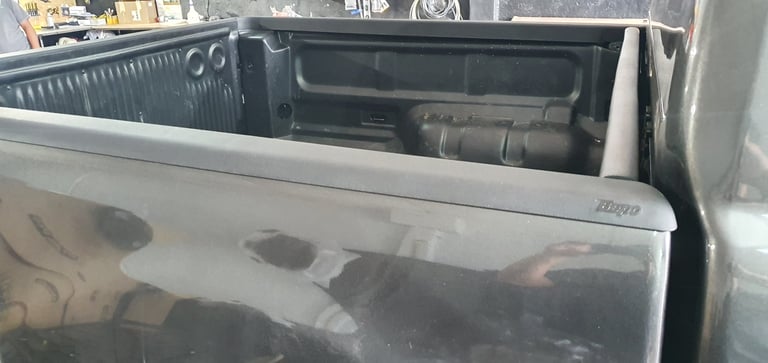Open truck bed with plastic liner and dark interior visible, showing bed compartment storage area