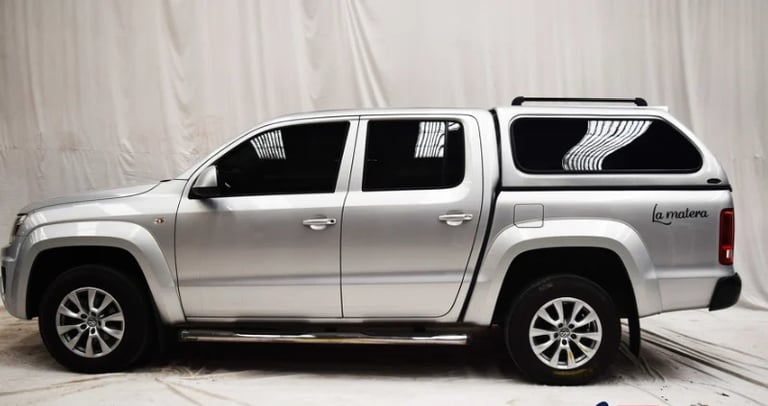 Silver pickup truck with tonneau cover parked against white backdrop in studio setting