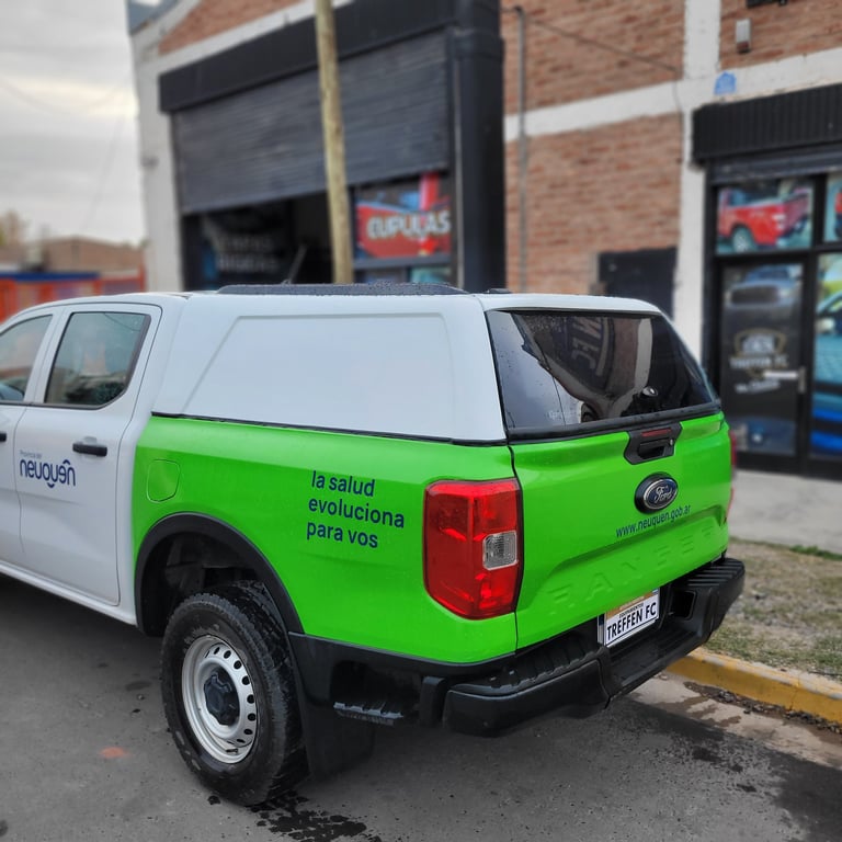 White and green pickup truck parked in front of a brick commercial building