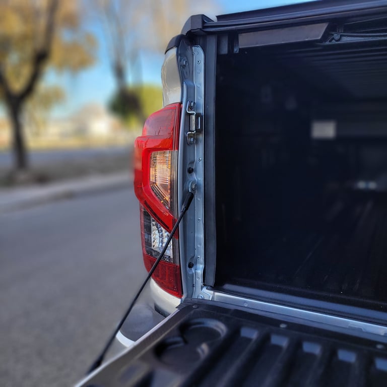 Close-up of a pickup trucks red taillight and open bed with blurred street background