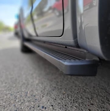 Close-up of a gray pickup trucks side with door and running board on a paved street