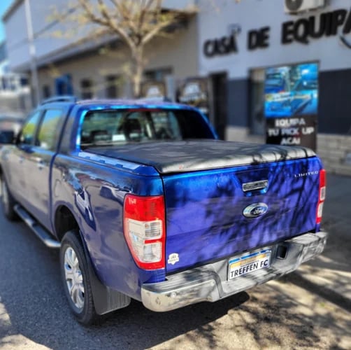 Blue Ford Ranger pickup truck with tonneau cover parked outside equipment shop