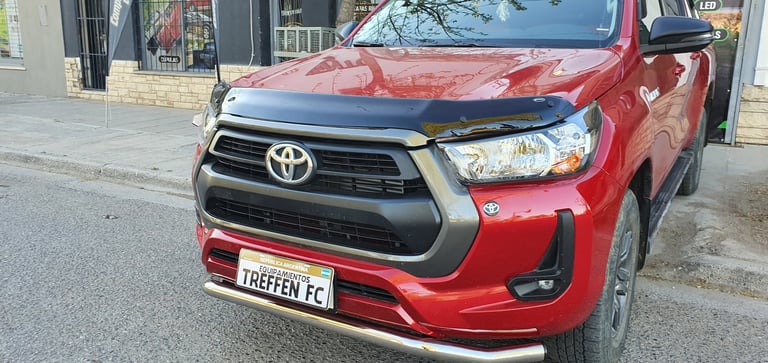 Red Toyota pickup truck with custom license plate parked on urban street