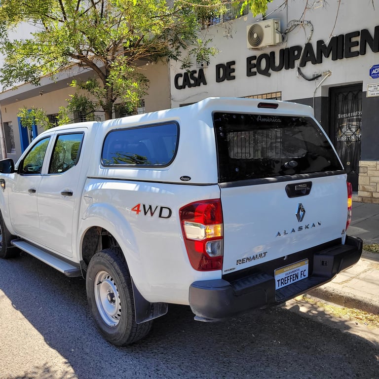 White Renault 4WD pickup truck with canopy parked on street, Casa de Equipamiento building visible in background