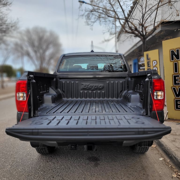 Rear view of a black pickup truck with open bed tailgate, showing ridged bed liner and cab details
