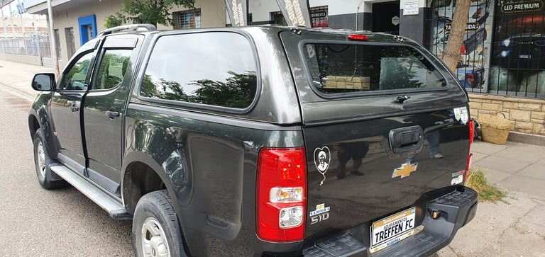Black Chevrolet pickup truck with crew cab parked on a street, showing rear and side view with red taillights and UK license plate