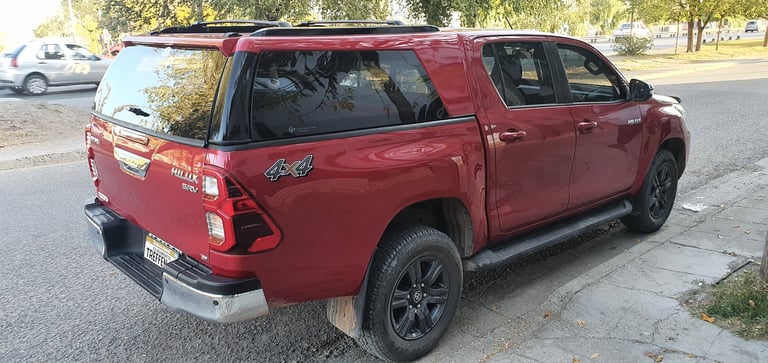Red Toyota pickup truck parked on street, rear three-quarter view showing truck bed and side profile