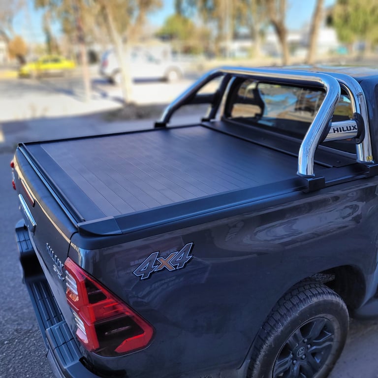 Blue pickup truck with tonneau cover and roll bar in a residential driveway