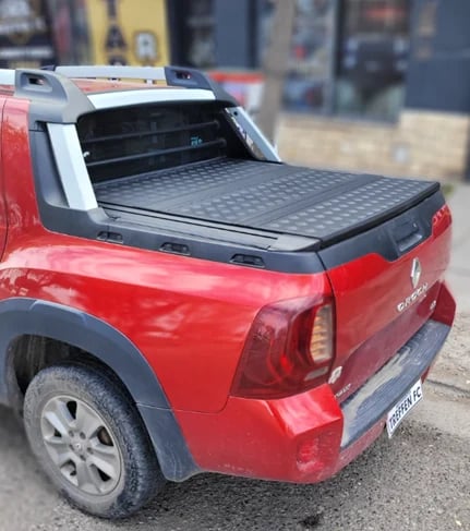 Red pickup truck with open tonneau cover displayed at outdoor dealership