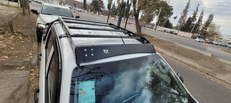 White SUV with roof rack and cargo carrier parked on street with palm trees in background