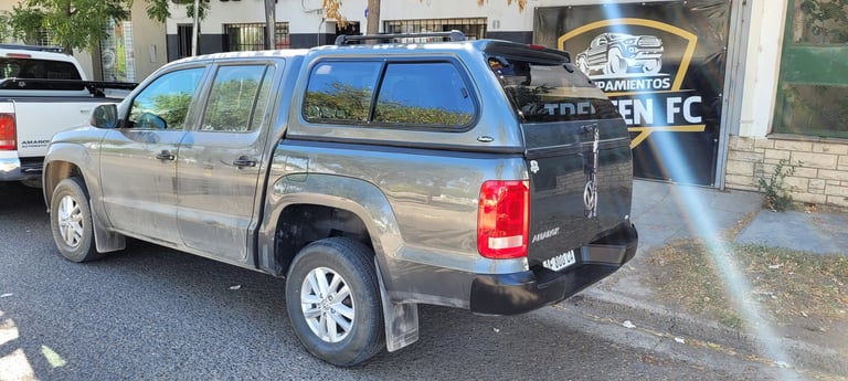 Silver and black pickup truck parked on street being sprayed with water pressure wash
