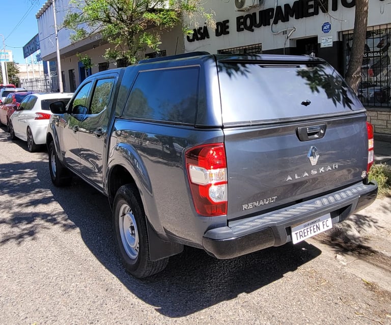 Gray Renault Alaskan pickup truck parked on a sunny street with storefront in background
