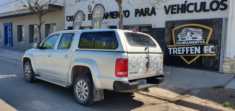 White pickup truck parked outside a vehicle repair shop with Spanish signage