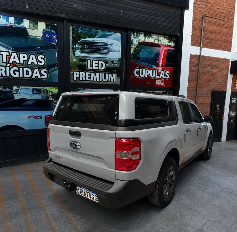 White pickup truck parked outside auto shop with signage for rigid covers and LED lights