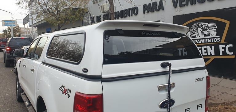 White pickup truck with canopy parked on street near sports facility signage