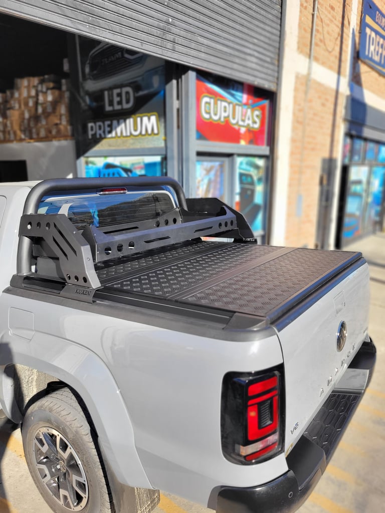 White pickup truck bed with black tonneau cover and cargo rack installed in front of auto parts store
