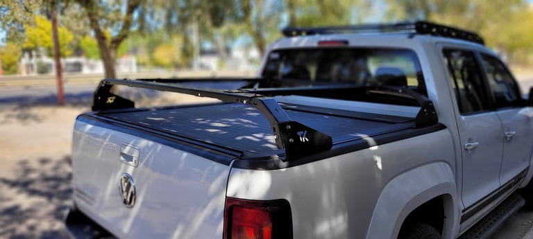 White pickup truck with black tonneau cover and roof rack in a sunny residential area with trees