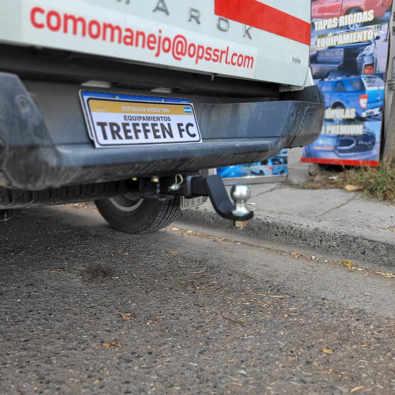 Close-up of a vehicle rear showing a Treffen FC license plate and towing hitch on asphalt ground