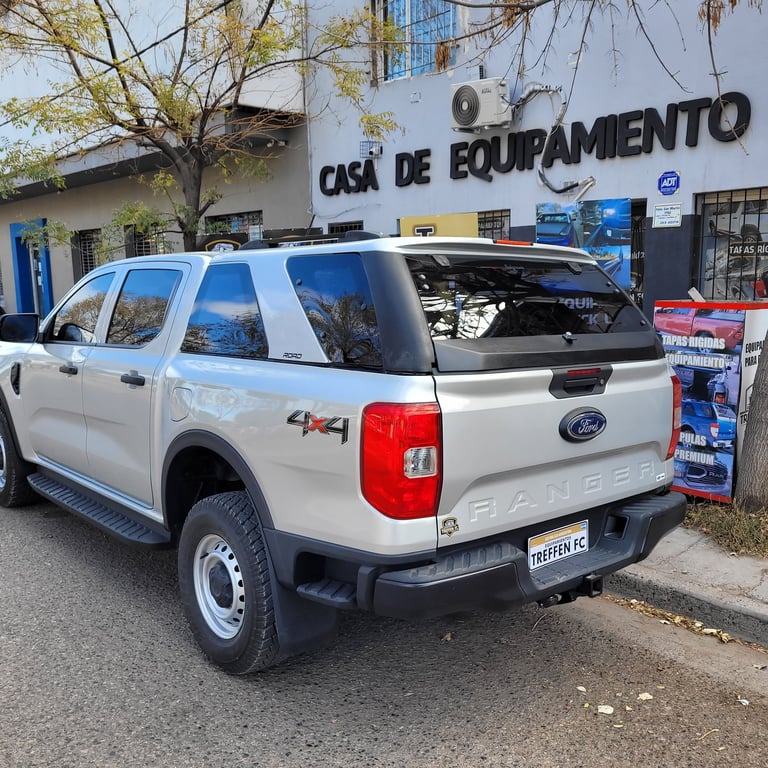 White Ford Ranger pickup truck parked outside a Casa de Equipamiento shop