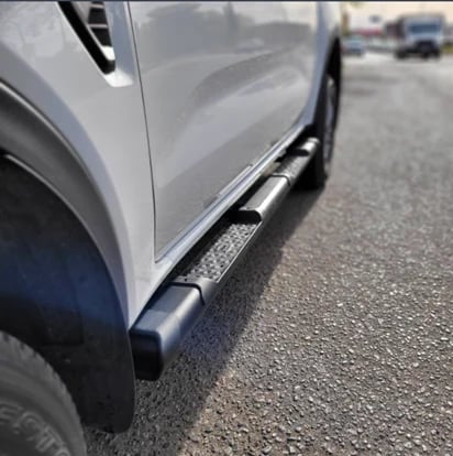 Close-up of a silver vehicle with a black side step running board installed along the lower edge of the door