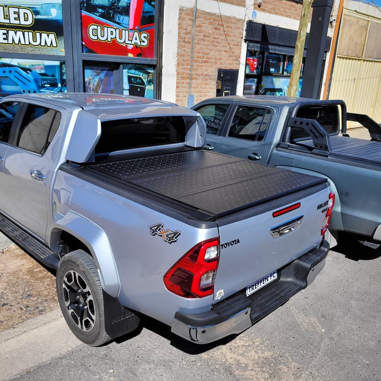 Silver Toyota pickup truck with open tonneau cover displaying bed liner in outdoor parking lot