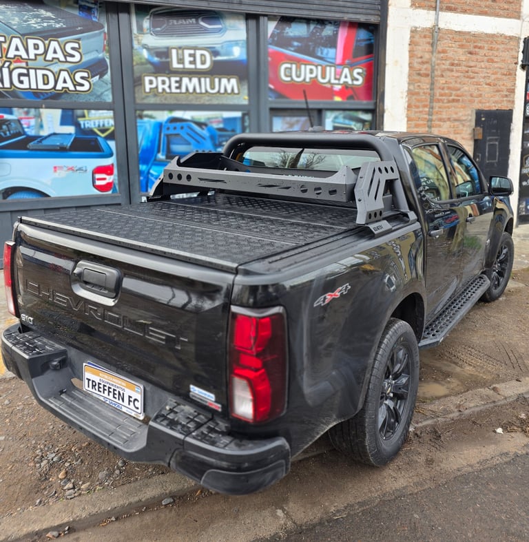 Black pickup truck with tonneau cover parked outside a shop with Spanish signage