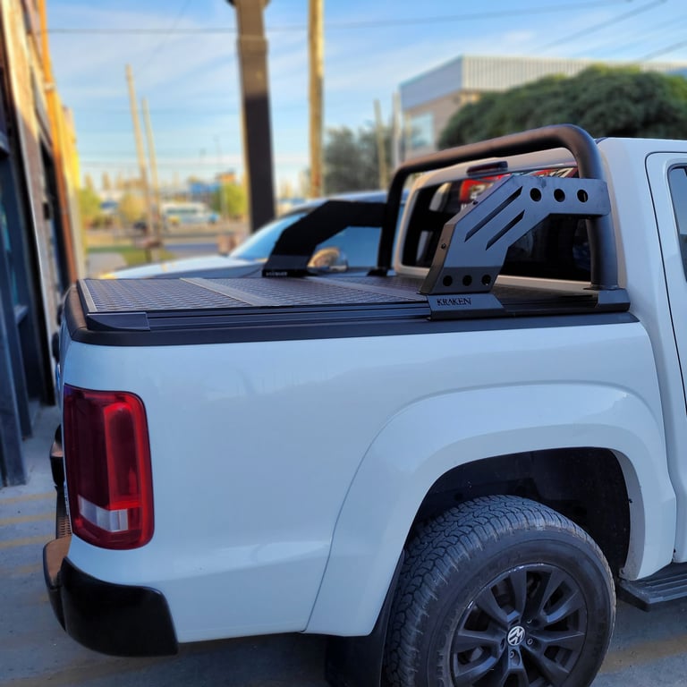 White pickup truck with tonneau cover and roof rack, parked in desert lot with palm trees and buildings visible