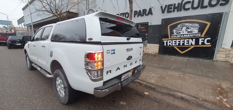 White Ford Ranger pickup truck parked at a vehicle dealership lot with signage visible in background