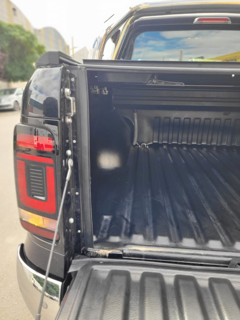 Open truck bed with black ridged liner and red taillight visible on parked pickup truck