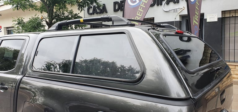 Silver pickup truck with roof rack and canopy top, parked in outdoor lot