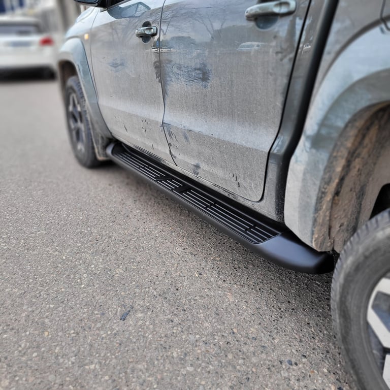 Damaged white pickup truck with dented door panels and dirt streaks in parking lot