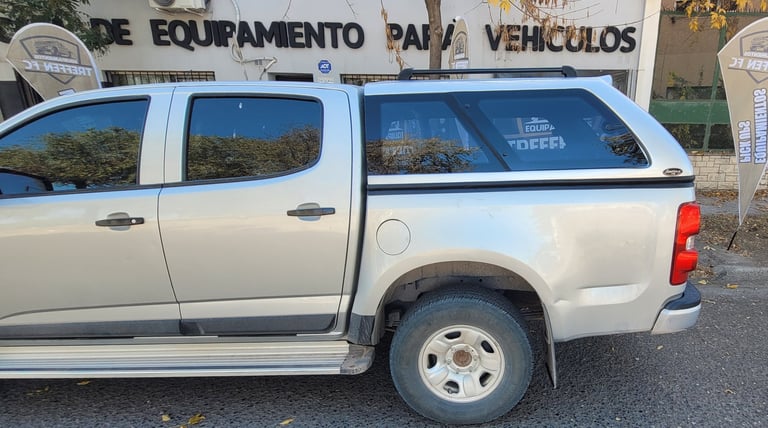 White pickup truck with cab topper at a vehicle dealership with signage in background