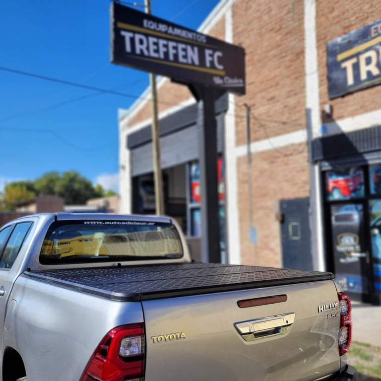 Silver Toyota pickup truck with tonneau cover parked outside Treffen FC sports facility storefront