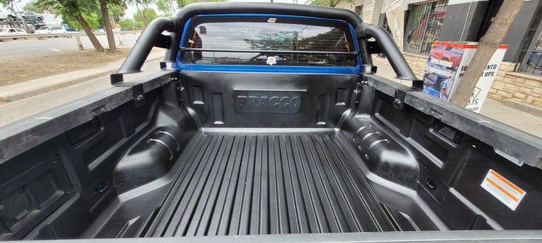 Empty blue pickup truck bed with black liner and ribbed floor, viewed from the tailgate