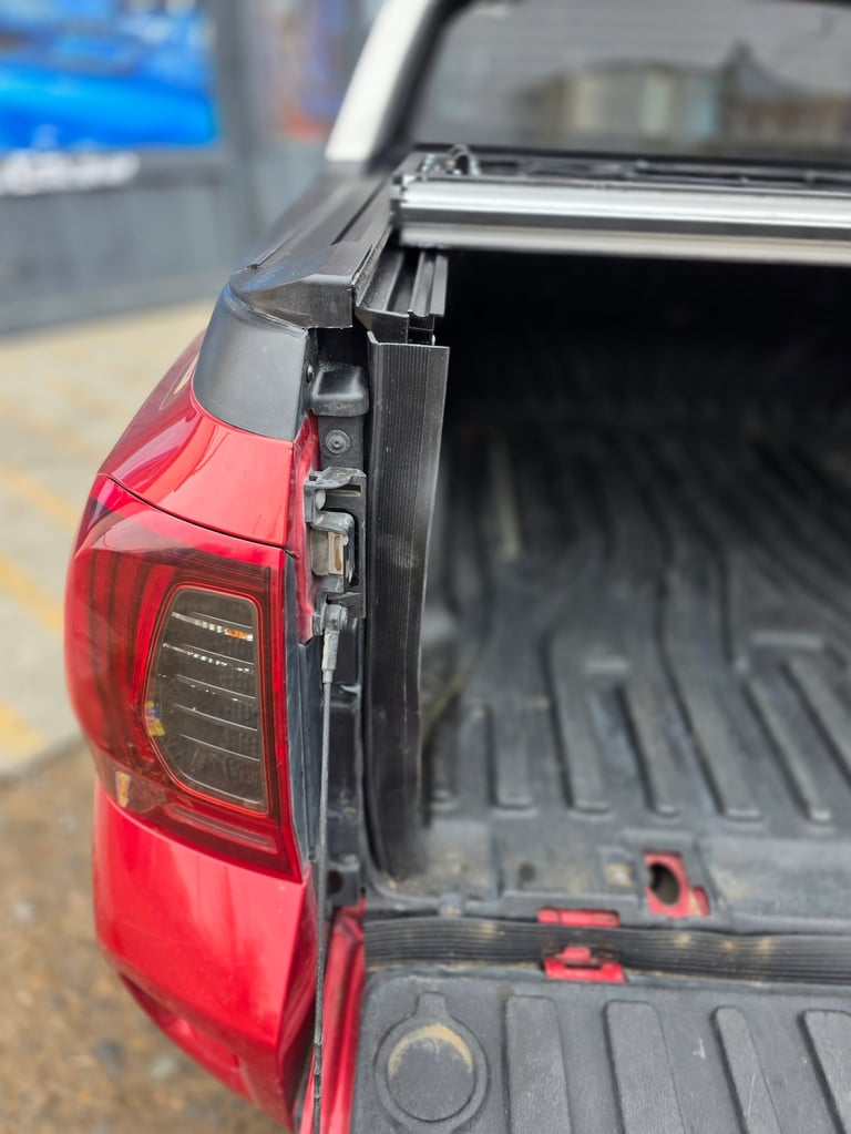 Close-up of truck bed with open tonneau cover showing red taillight and dark cargo bed liner