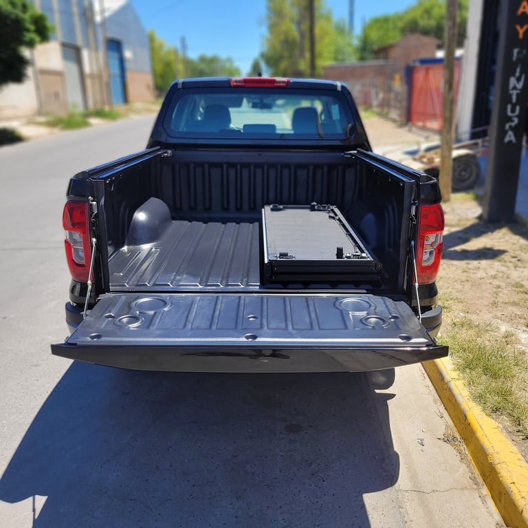 Blue pickup truck with open bed and tonneau cover displayed at an auto shop