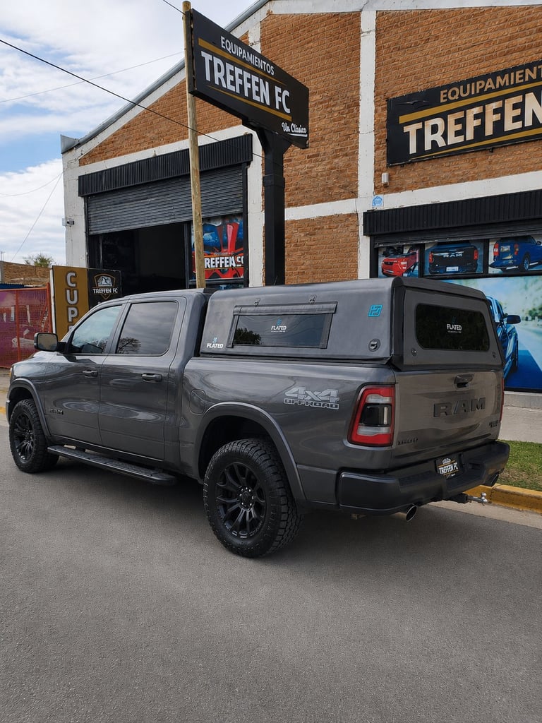 Gray pickup truck with canopy parked outside a brick building with TREFFEN FC signage