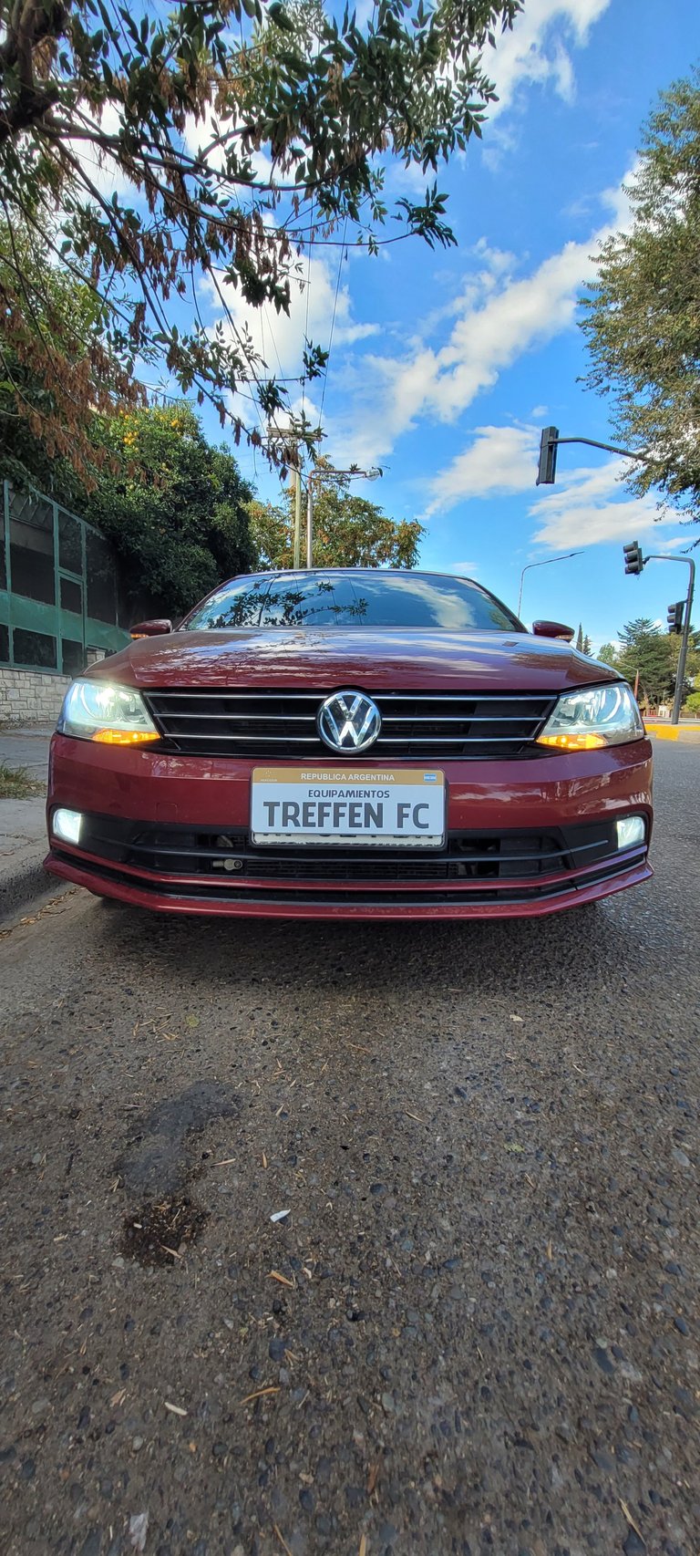 Maroon Volkswagen sedan parked on street with TREFFEN FC license plate and blue sky background