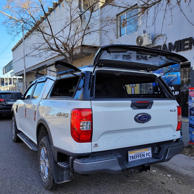 White Ford pickup truck with roof rack parked in front of industrial building